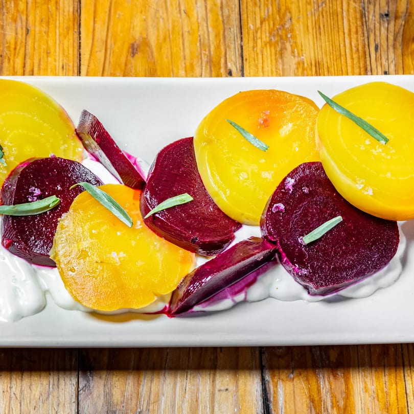 Stone House's vibrant beet salad with yellow and red beets, fresh herbs, and creamy sauce.