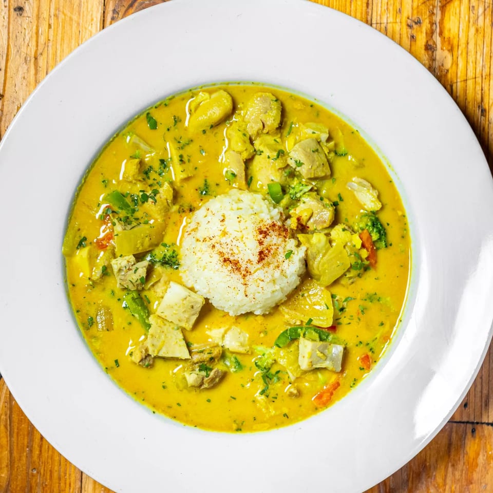 Stone House's yellow curry with chicken, vegetables, and a scoop of rice in a white bowl.