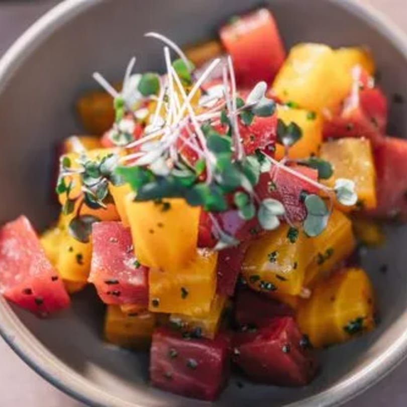 A vibrant Stone House beet salad with red and yellow diced beets, topped with microgreens.