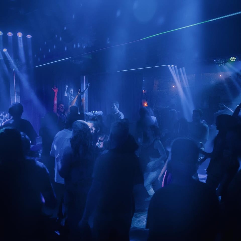 A lively crowd dances under blue lights and spotlights at Stone House restaurant.