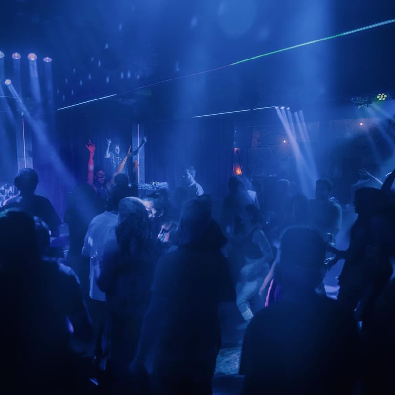 A lively crowd dances under blue lights and spotlights at Stone House restaurant.