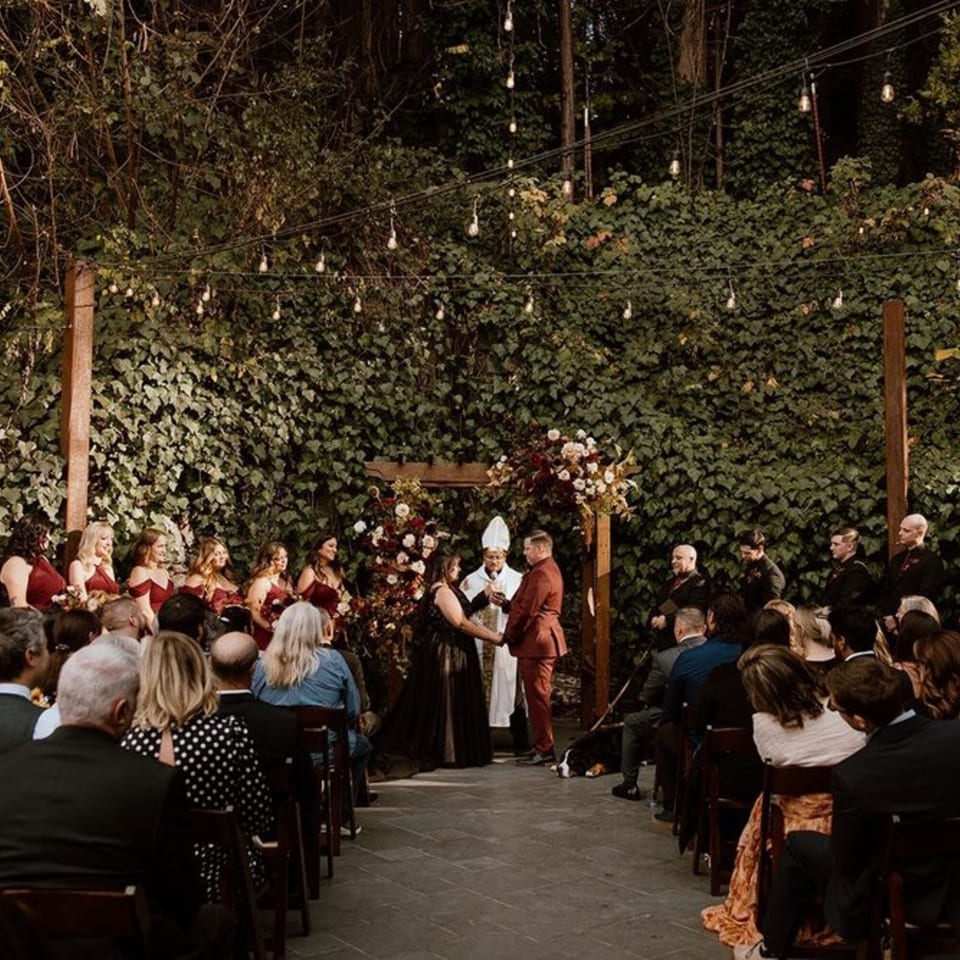 Outdoor wedding ceremony at Stone House, with guests seated and string lights overhead.