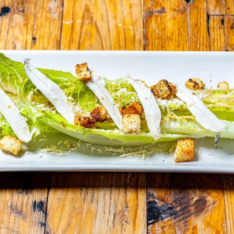 Stone House Caesar salad with romaine lettuce, white anchovies, croutons, and grated cheese.