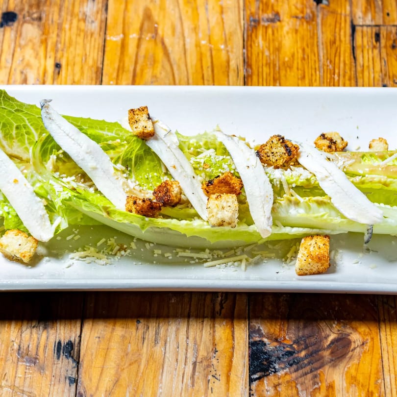 Stone House Caesar salad with romaine lettuce, white anchovies, croutons, and grated cheese.