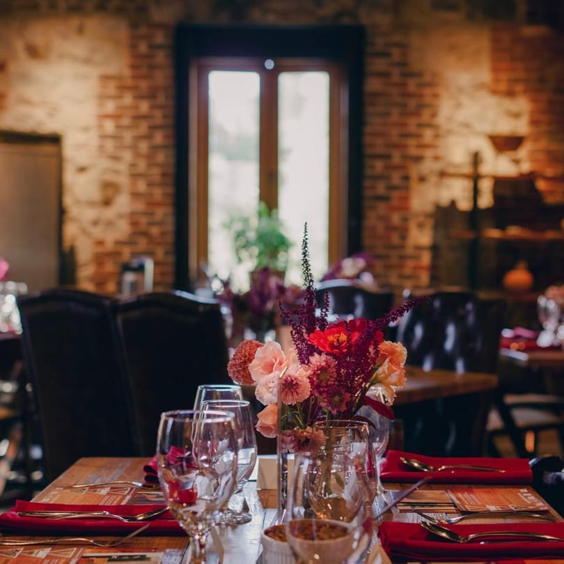A set table at Stone House restaurant with red napkins, silverware, glasses, and a floral centerpiece.