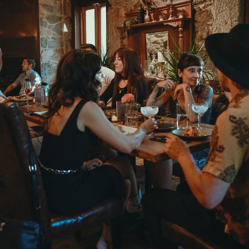 Patrons enjoying drinks and food at Stone House, a new-American restaurant with stone walls and warm lighting.