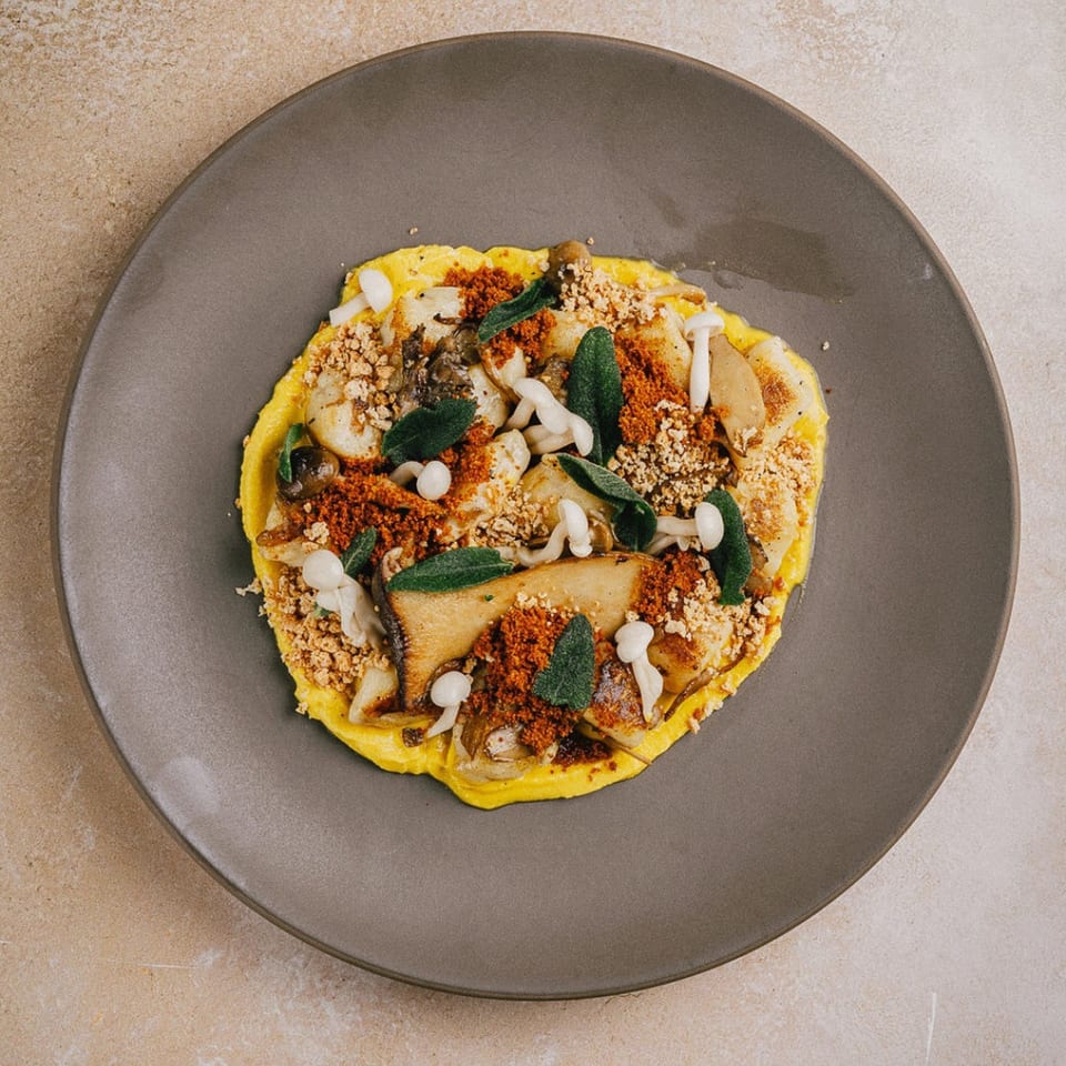 Stone House's New American dish featuring mushrooms, red spice, and herbs on a yellow base.